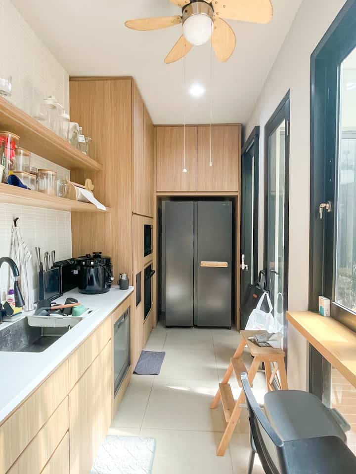 A long kitchen space with harmonious white and wood tones, featuring clean storage and a modern Japandi-style interior ambiance