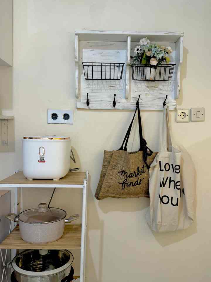 White-toned kitchen space with beige kitchenware, featuring wall-mounted storage and a kitchen cart in a tidy arrangement