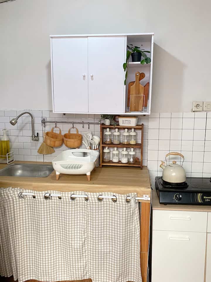 Small kitchen space featuring natural wood tones and white colors, neatly organized with a simple and clean atmosphere