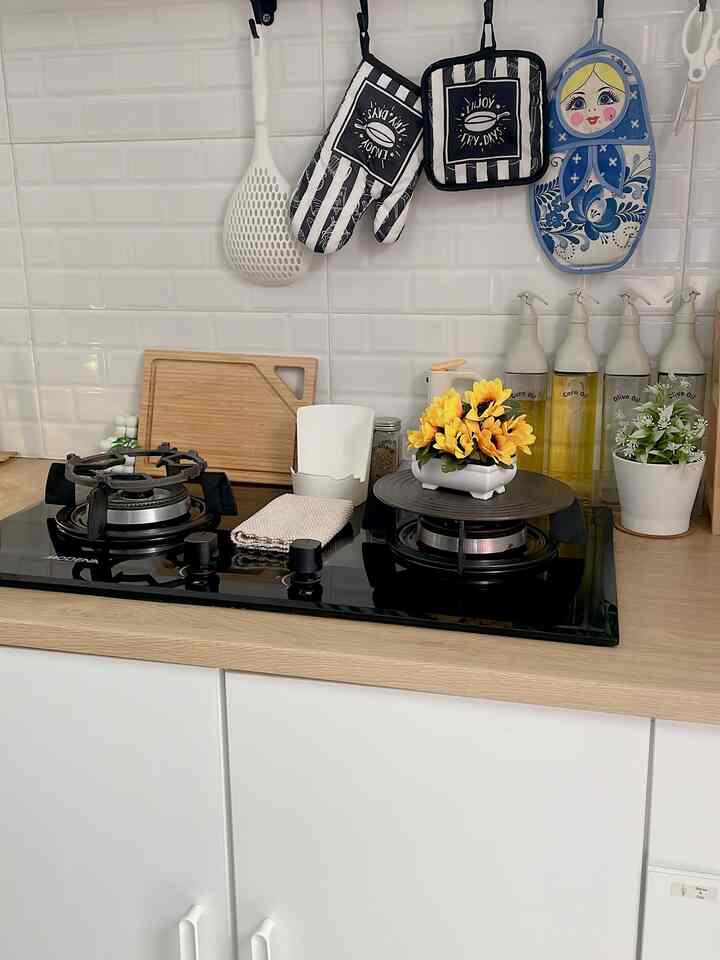 Minimal kitchen featuring wood tone countertop and black gas stove, decorated with plants and kitchen utensils