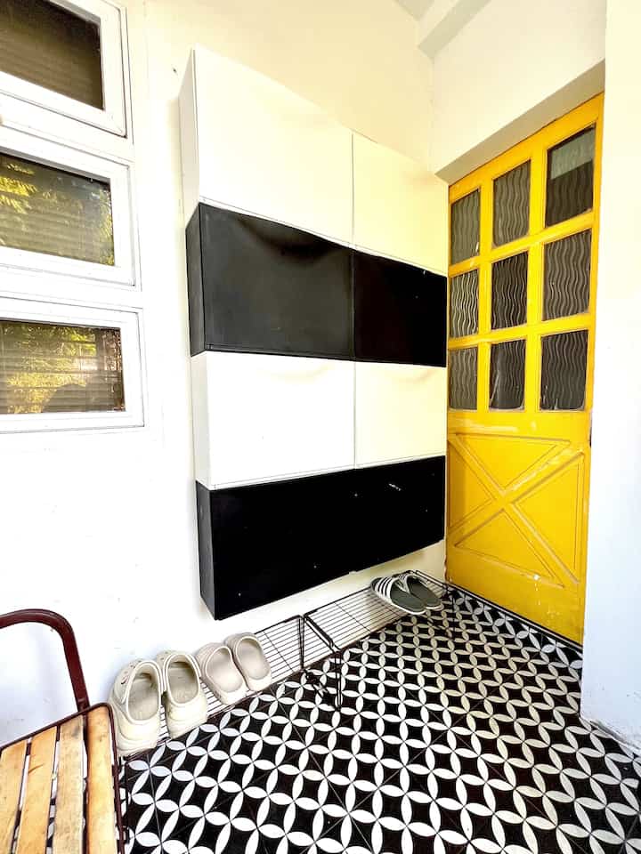 Entrance space with black and white shoe cabinet and a yellow door accent, featuring a simple and clean design