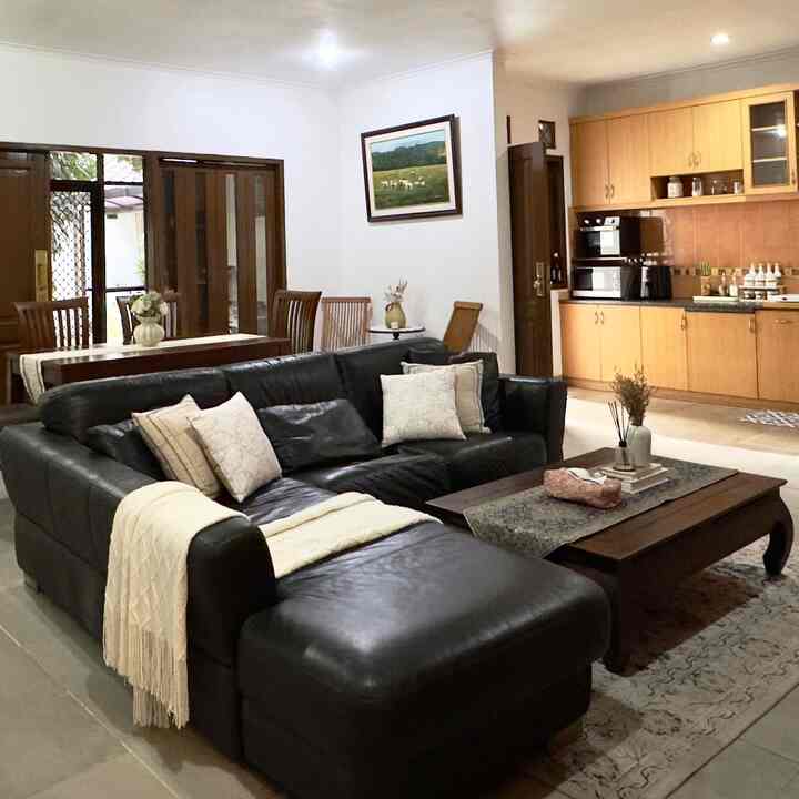 Natural brown-toned open plan living room featuring black leather sectional sofa and wooden coffee table with cozy atmosphere