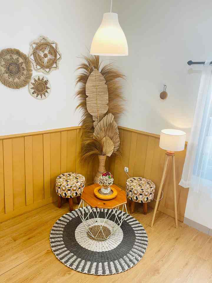 Small dining corner featuring natural wood tones, white pendant light, patterned stools, and a round woven rug creating a cozy atmosphere