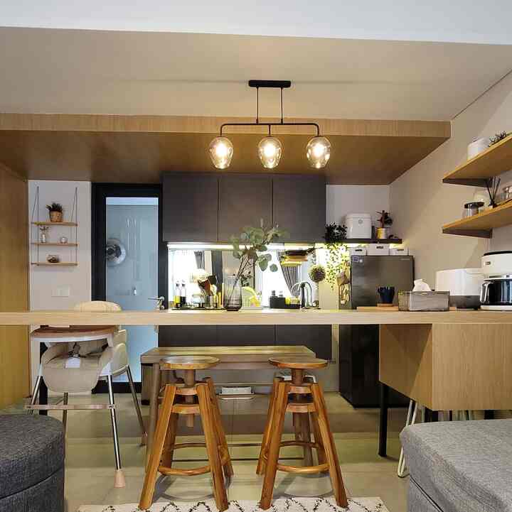 Warm wood tones and black kitchen cabinetry blend in a compact two-person kitchen-dining space featuring a home cafe setup beneath pendant lights