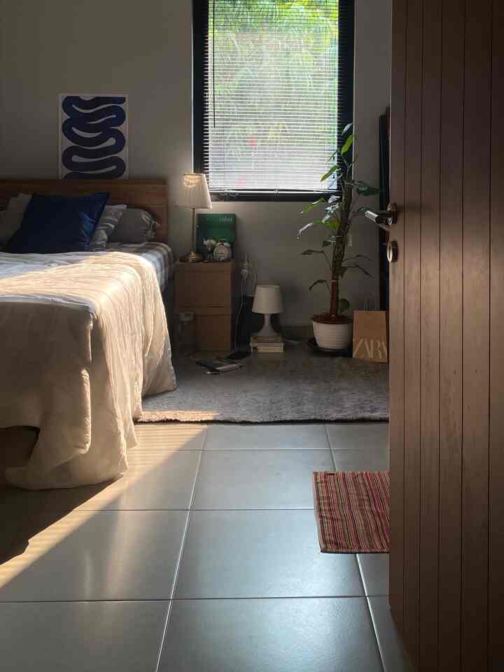 Natural wood tones and white blend in a bedroom corner featuring a bed, nightstand, and plant, creating a cozy and bright space