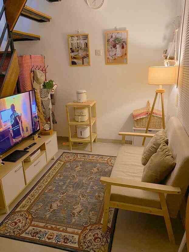 Beige and wood tone compact living room featuring a sofa bed and TV stand, creating a cozy and natural atmosphere