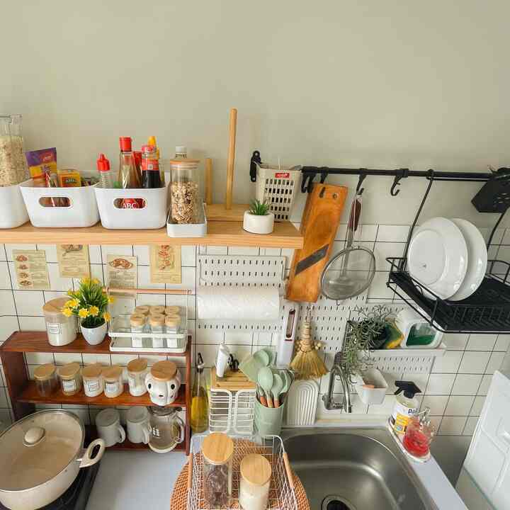 Compact kitchen in harmonious white and wood tones, featuring wall storage and cooking utensils for an efficient and cozy space