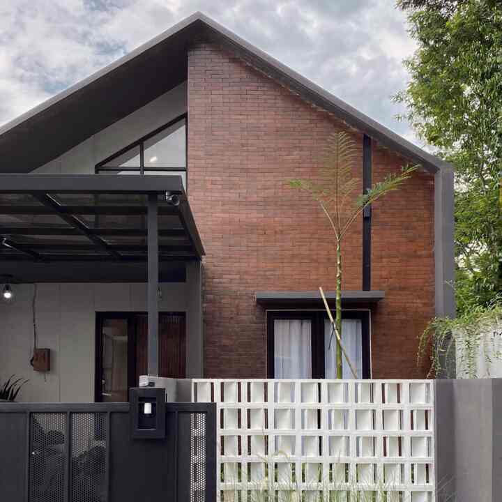 Exterior view of a modern K-style house featuring red brick facade and black metal entrance gate