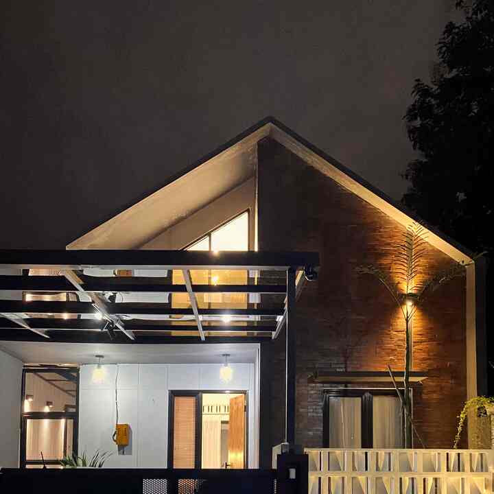 Night view of a detached house with red brick and white facade, highlighting outdoor lighting and entrance area