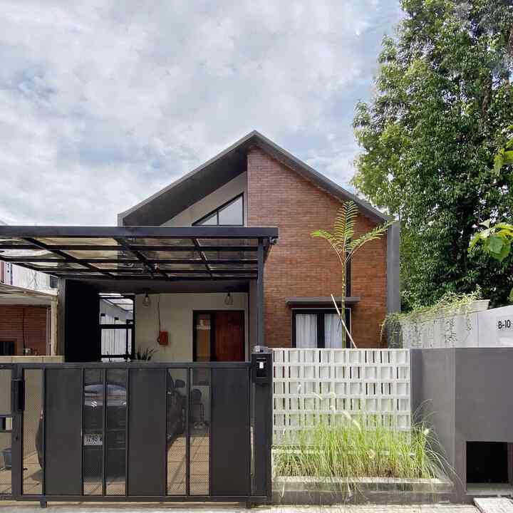 Industrial Scandinavian style single-story house facade featuring dark gray metal elements and brown brick walls, with high ceilings and a modern metal canopy