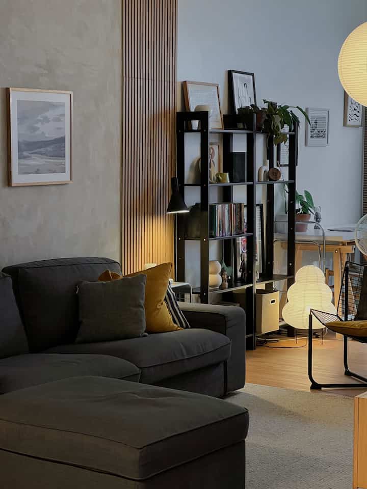 Minimal Japandi living room with gray sofa and wood-tone wall, spacious and open atmosphere