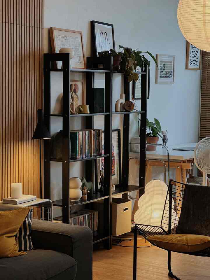 Black and wood tone living room featuring a black armchair, bookshelf, and floor lamp creating a cozy atmosphere
