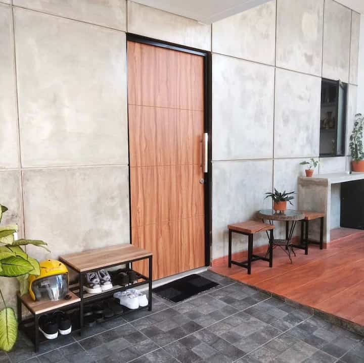 Entrance featuring gray concrete walls and a wood-toned door with shoe storage bench, creating a clean and minimalistic space