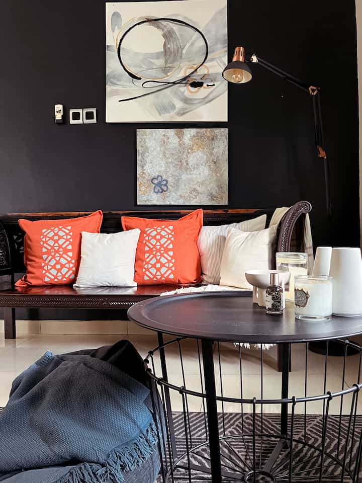 A living room with dominant black and orange tones featuring a wooden bench with cushions and a metal coffee table in a simple modern style