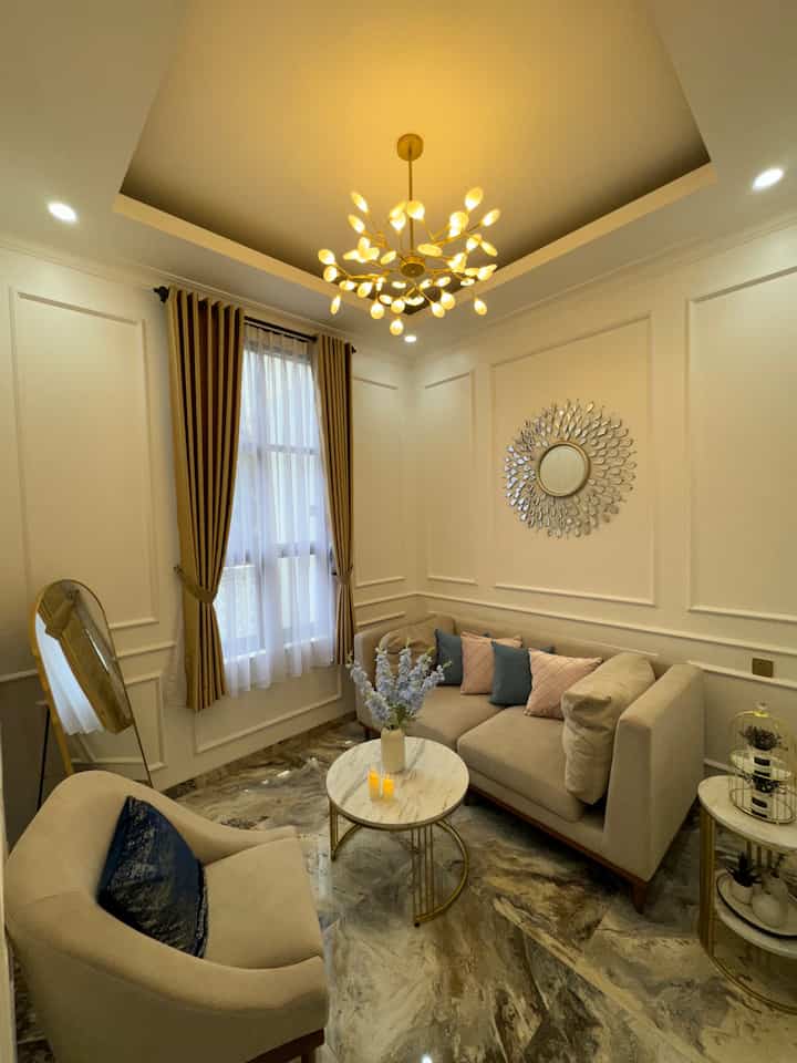 A small modern living room in gold and white tones featuring beige sofas and a round coffee table with cozy atmosphere