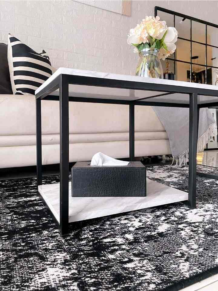 Modern living room in white and black tones featuring a marble coffee table and striped cushions in a simple setting