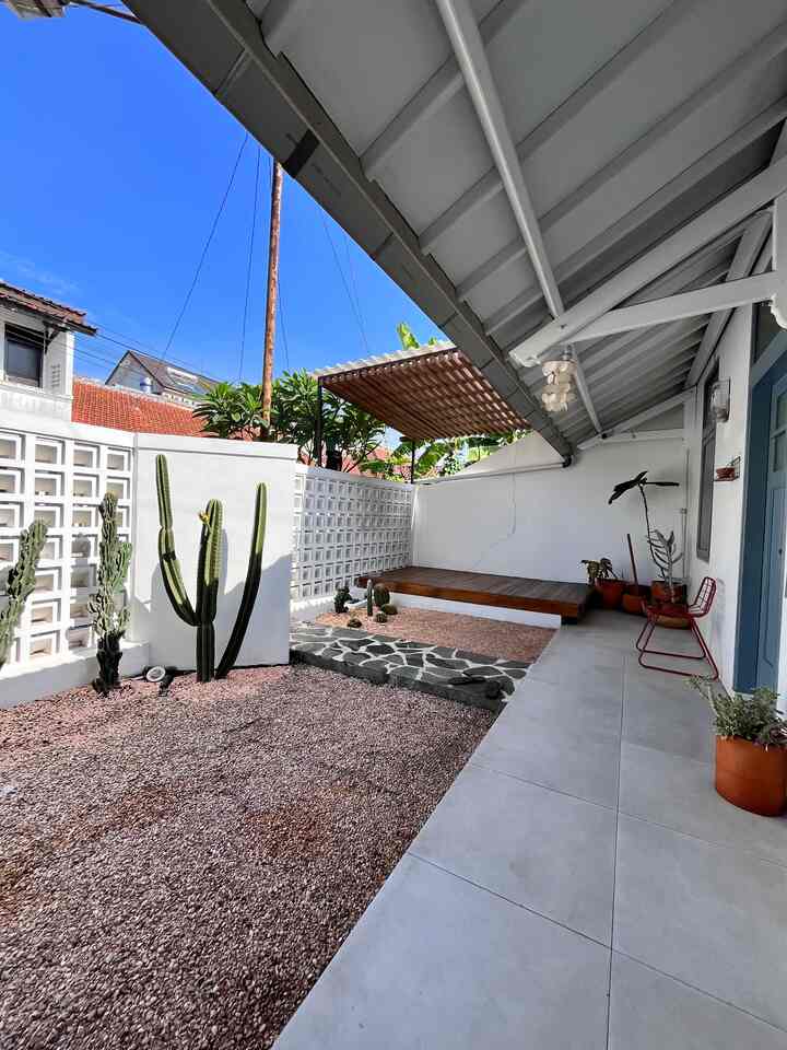 Outdoor veranda space with clear blue sky, featuring natural tones, cacti, and potted plants creating a relaxing garden atmosphere