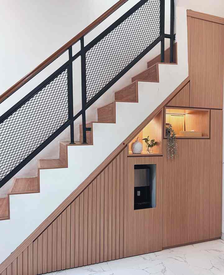 Modern stair area with wood tones and white walls featuring storage compartments under stairs and black metal railing