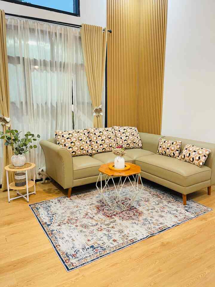 Wood tone and white living room featuring L-shaped sofa, Turkish carpet, and beige curtains with a simple atmosphere