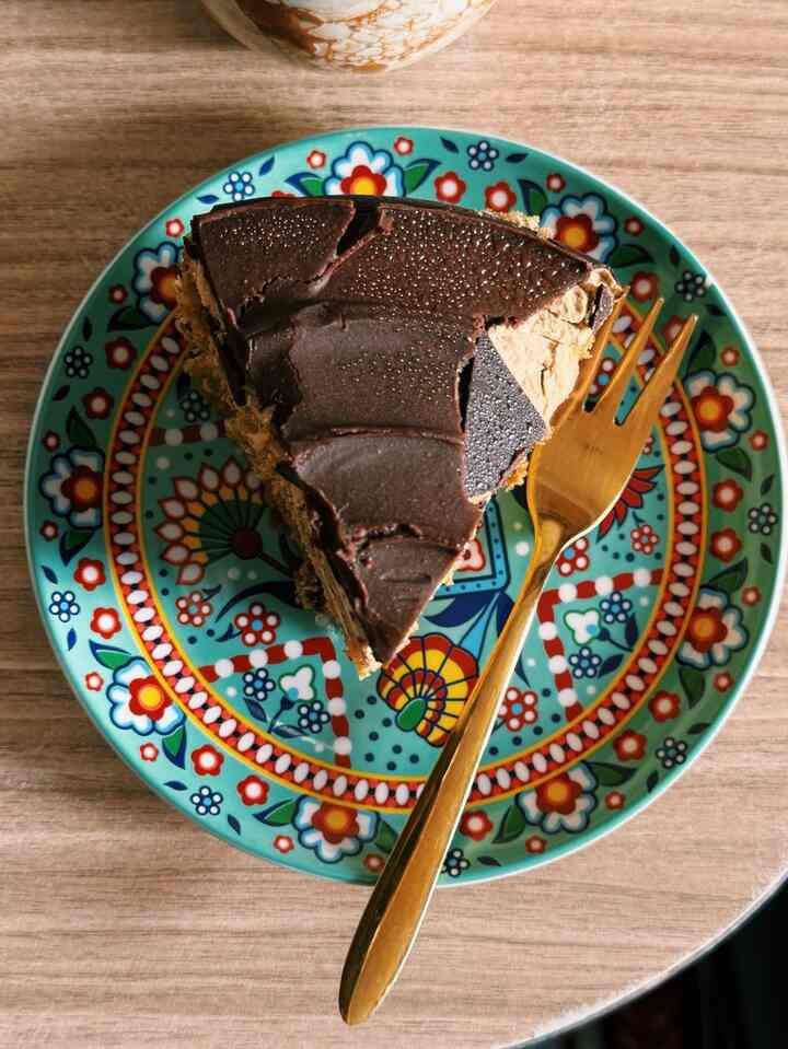 Colorful patterned plate featuring a slice of chocolate cake and a gold fork on a wooden table