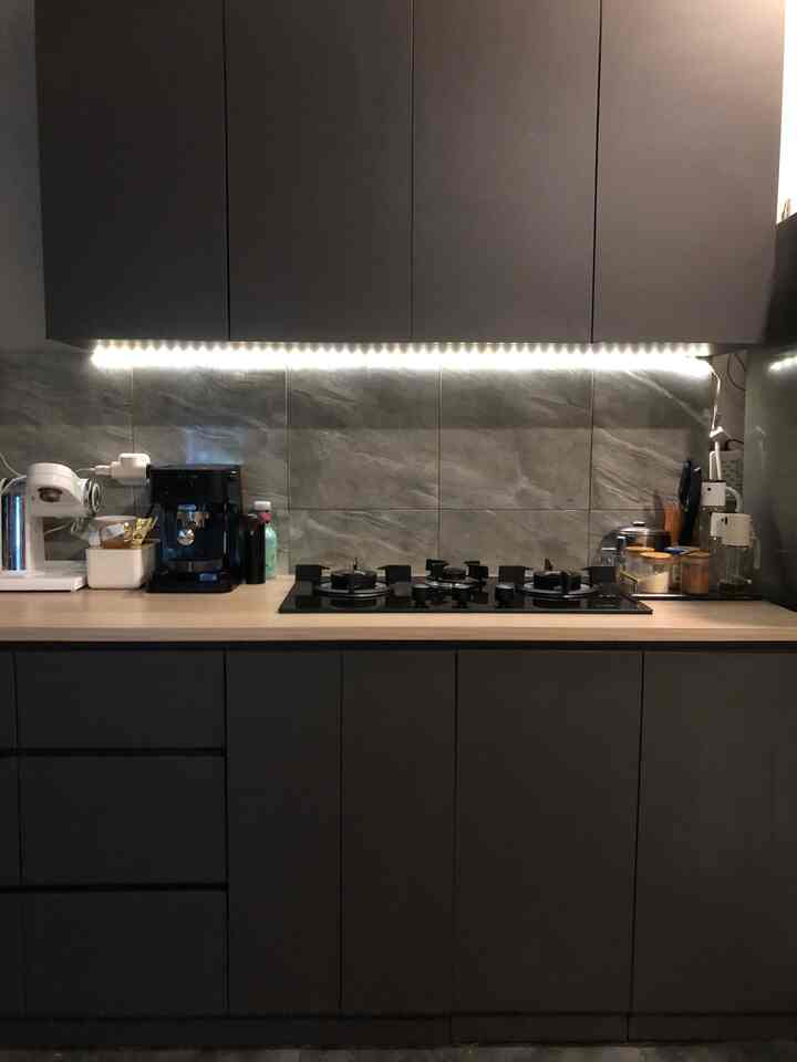 Charcoal-toned kitchen with gas stove and LED strip lighting, featuring a simple modern design