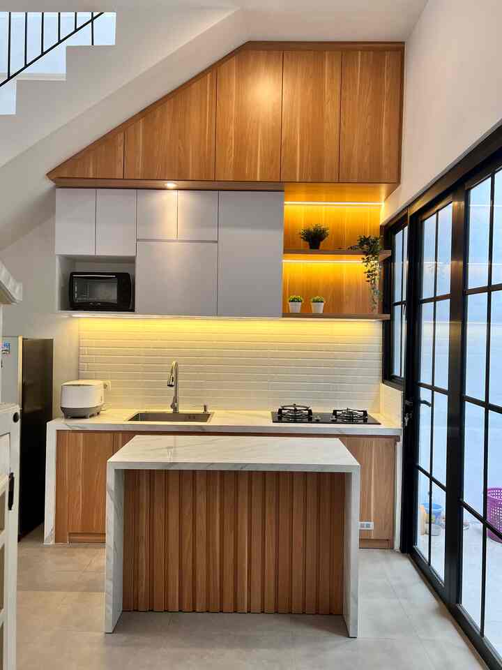 Wood tone and white kitchen space featuring clean, modern design with artificial plants and LED strip lighting accents