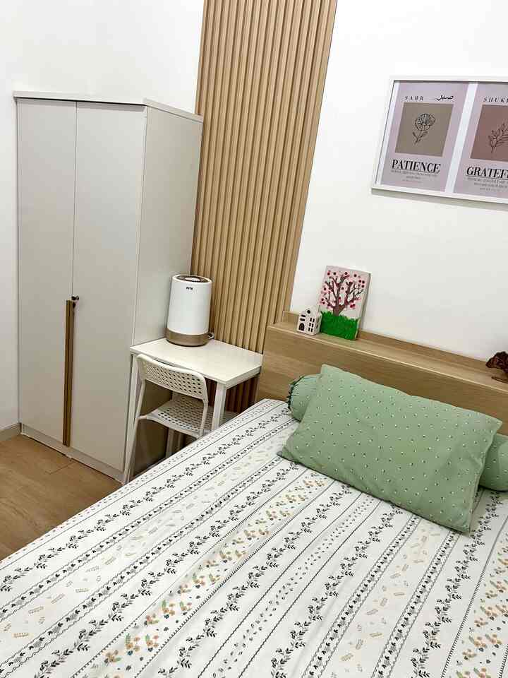 A bedroom with white and wood tones, featuring a wardrobe and desk arranged in a cozy space