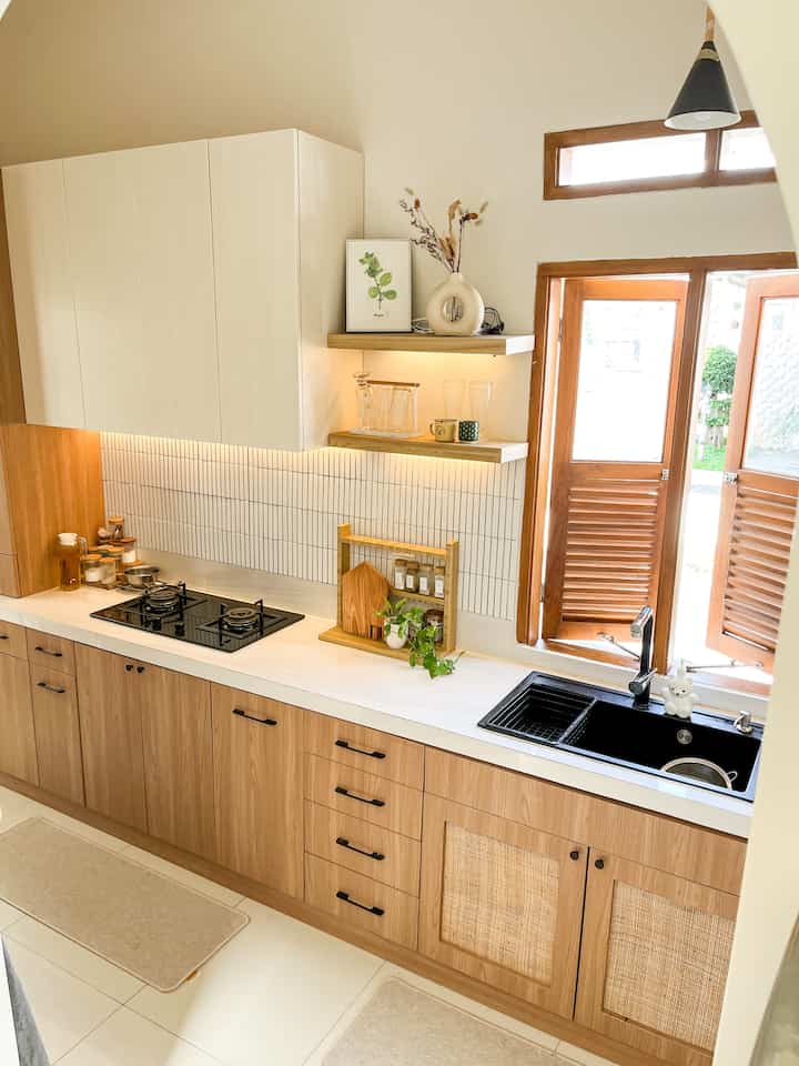 Dekorasi Dapur Segaris •

Tema utama di dapur ini masih white and wood, tapi karena kompor berwarna hitam, kami pun memilih sink berwarna hitam juga agar si kompor ada temannya ☺️ begitupun lampu gantung dan handle, dibuat hitam agar ada warna kontras di dapur.

Ketika mendesain kitchen set, ada beberapa hal yang menjadi poin utama :
1. Kabinet menggunakan 2 warna (disini menggunakan warna putih dan coklat) dengan aksen rotan.
2. Kombinasi kabinet dan ambalan agar tidak monoton. Ambalan juga sangat baik untuk dekorasi dapur.

Aku tidak meletakkan banyak barang di dapur agar dapur terkesan bersih dan lega. Hanya ada rak bumbu yang sekaligus menjadi pajangan. Dengan begitu, tidak terlalu sulit menata dan membersihkan table top dapur.

Agar terlihat lebih homey, aku menambahkan vas bunga, rak gelas dan hiasan frame di ambalan. Ada juga tanaman hijau agar suasana di dapur jadi lebih fresh!

#KitchenStyling #IdeDekorDapur #MakeoverDapur #DapurCantik #WhiteandWoodKitchen #DapurMinimalis #DekorasiDapur
