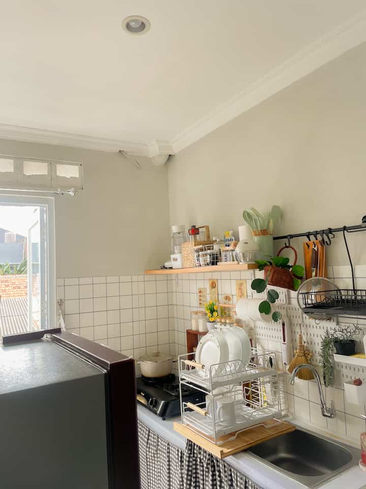 Halo sahabat O!House🩵 beginilah penampakan dapur mungilku. Ya memang masih jauh dari kata sempurna, karena belum punya kitchen set dan peralatan bagus lainnya dikarenakan aku masih ngontrak nih, jadi aku ga banyak bisa merubah tatanan dapur dikarenakan terbatasnya space. walau minim space bukan berarti kita gabisa bikin dapur jadi cantik dan estetik ya moms❣️ kebetulan aku menyukai styling dari japandi jadi aku menerapkan japandi style untuk mendekor dapurku ini, nah untuk mengakali tata letak dapur biar ga sempit dan tetap terorganisir aku memilih mengakali barang yang bisa aku tempel di tembok seperti menggunakan ambalan yang aku posisikan tepat diatas komporku memasak, kenapa? Ya selain untuk menambah keestetikan mata juga aku memikirkan efisiensi dan fungsionalitas jikalau saat memasak aku membutuhkan perintilan atau perbumbuan aku bisa langsung gercep ngambilnya. Aku menyusun beberapa perintilan dapur dengan meletakkannya diatas storage agar tetap terlihat rapih dan cantik. Kemudian, untuk beberapa barang yang sering digunakan aku memilih menggunakan pegboard yang aku tempel di dinding tepat diatas sink cuci piring agar bisa langsung digantung setelah dicuci. Aku menambahkn beberapa tanaman artificial sebagai hiasan dekorasi agar dapur ini tetap terkesan fresh dan cozy. Penggunaan pegboard ini juga sangat fleksibel karena bisa di bongkar pasang dan lobang yang ada di setiap sisi boradnya sangat bisa difungsikan untuk menggantung beberapa perintilan dapur yang sering kita gunakan seperti tissue gulung dll. Walau dapur ini minim space tapi alhamdulillhnya terdapat pintu kaca yang cukup besar dan di sisi pintunya itu didesain menggunakan kaca full jadi untuk sirkulasi udara maupun cahaya sangat sangat aman, jadi walau sempit tapi ga pengap😁 doain yah aku bisa punya rumah sendiri dan bisa punya kitchen set juga biar masak tu lebih happy dan kalo kau ngedekor juga lebih bebas karena sudah milik sendiri. Semoga menginspirasi sahabat O!House ya🩵

#KitchenStyling
#IdeDekorDapur
#MakeoverDapur
#DapurEstetik
#DapurMinimalist