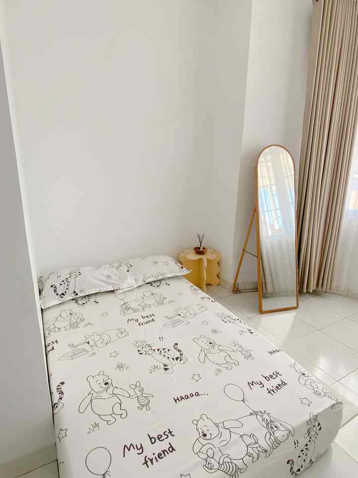 White and beige toned kids' room featuring a child's bed and a full-length mirror in a simple layout