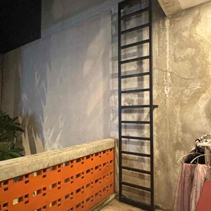 Natural-toned balcony featuring a black metal ladder and warm wall lighting creating a cozy atmosphere