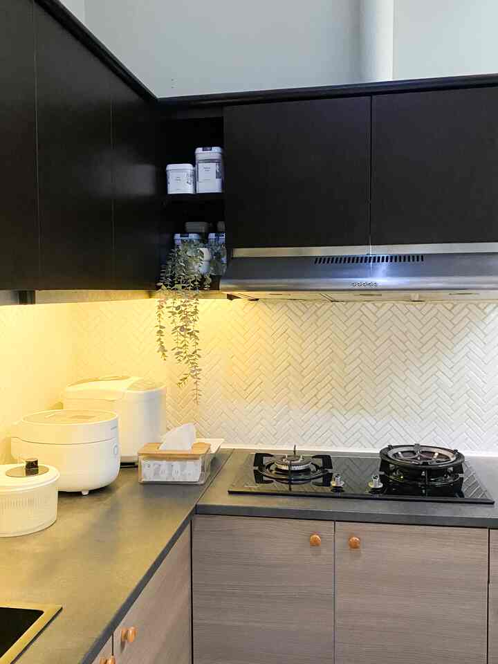 Compact kitchen with white tiled backsplash and modern cabinets, clean surface with artificial plant decoration