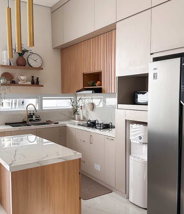 Dapur adalah area yang sangat penting di rumahku. Selain karena posisinya yang menyatu dengan living dan dining room, aku juga spend banyak waktu setiap hari di sini baik itu memasak untuk keluarga ataupun untuk santai mempersiapkan minuman favorit. Untuk temanya sendiri, aku memilih tema modern minimalist dengan paduan warna taupe, kayu, dan juga warna brushed gold.

Jadi penting sekali buat aku memiliki dapur yang tertata rapih agar enak dipandang dan juga nyaman untuk digunakan. Aku sendiri memiliki preferensi top table yang sebisa mungkin clean dan tidak banyak perintilan barang, agar tidak terlihat penuh. Karena itu, aku usahakan sebanyak mungkin untuk menata semua perintilan dapur di dalam kabinet, barang-barang elektronik seperti rice cooker dan air fryer di bawah island, dan semua elemen-elemen dekorasi aku tempatkan di ambalan khusus. Tempat sampah pun aku tempatkan tersembunyi di dalam salah satu kabinet atau istilahnya “pull-out trash bin” agar tidak mengganggu pemandangan dan juga tidak bau.

Untuk lighting, aku menggunakan beberapa kombinasi jenis lampu: LED strip di atas top table, track lamp, dan juga tube light berwarna gold sebagai salah satu focal point juga dari dapur ini. 

#KitchenStyling
#IdeDekorDapur
#MakeOverDapur