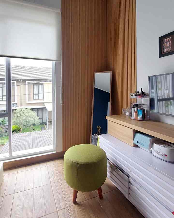 Bright living room with wood tone wall and floor, white storage cabinet, and a green stool positioned near window