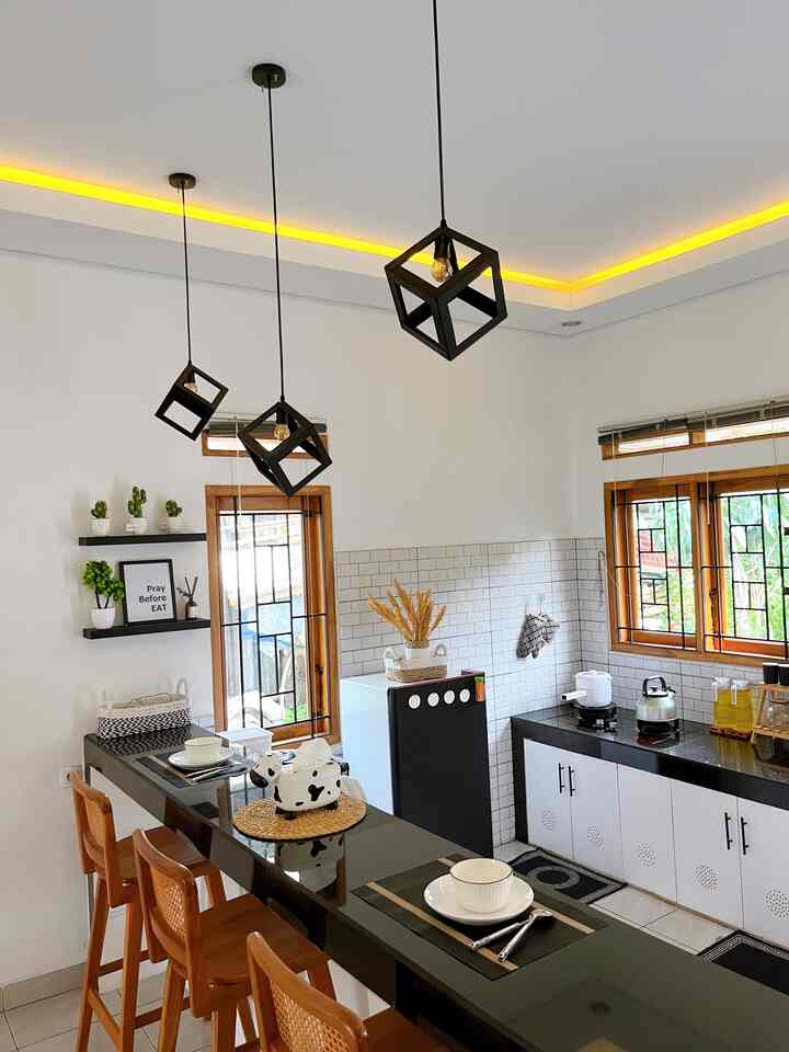 Natural tone compact kitchen with white walls featuring cafe-style bar stools and industrial pendant lighting