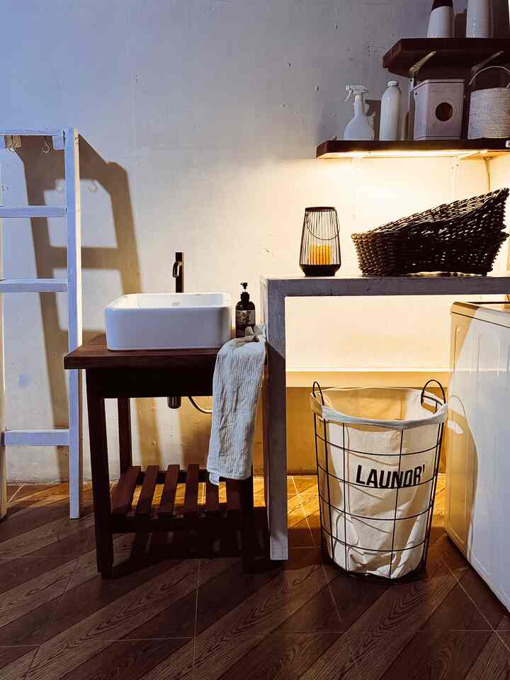Natural modern bathroom with brown wooden flooring and white washbasin, featuring storage baskets and warm lighting creating cozy atmosphere