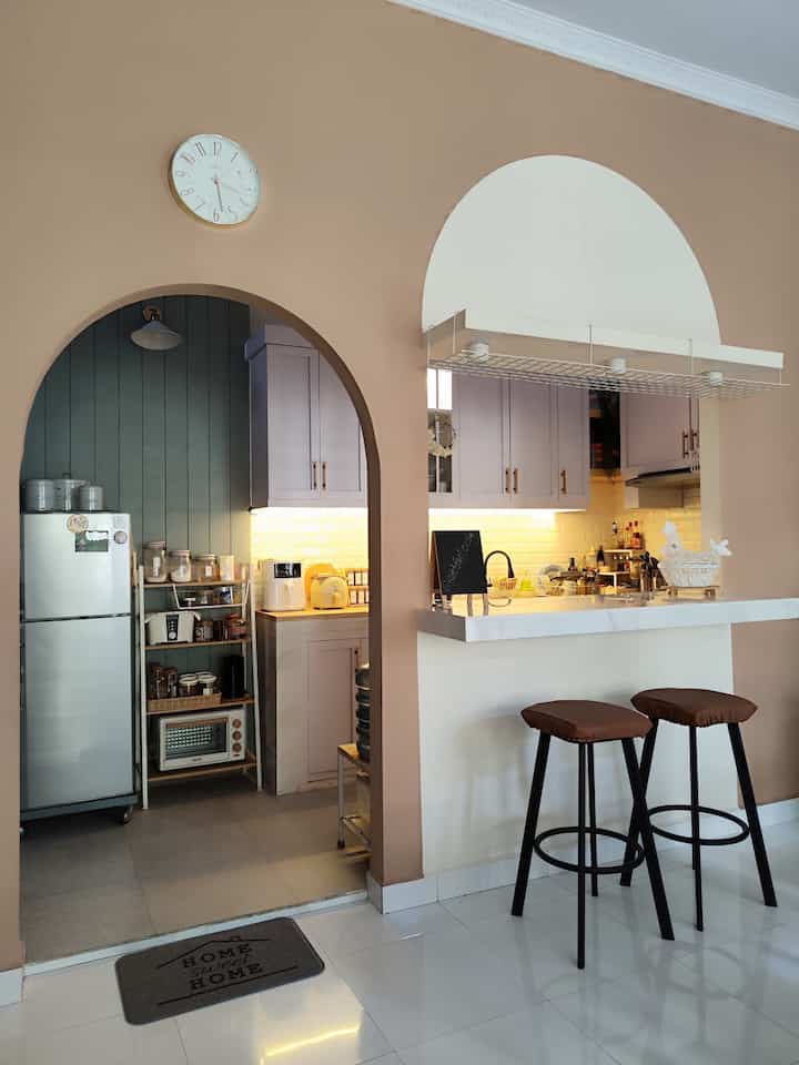 Beige-toned kitchen and home bar space featuring arch-shaped openings and bar stools with a warm atmosphere