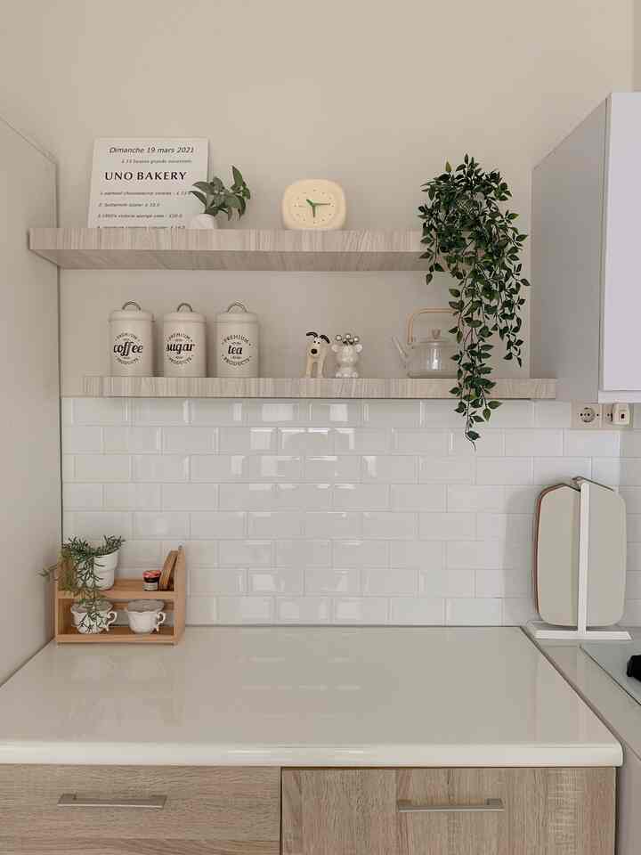 Natural color and white-tiled kitchen featuring wooden shelves and green plants creating a cozy atmosphere