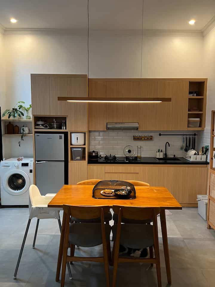 Bright white walled kitchen and dining space with wood tone furniture in Scandinavian Japandi style