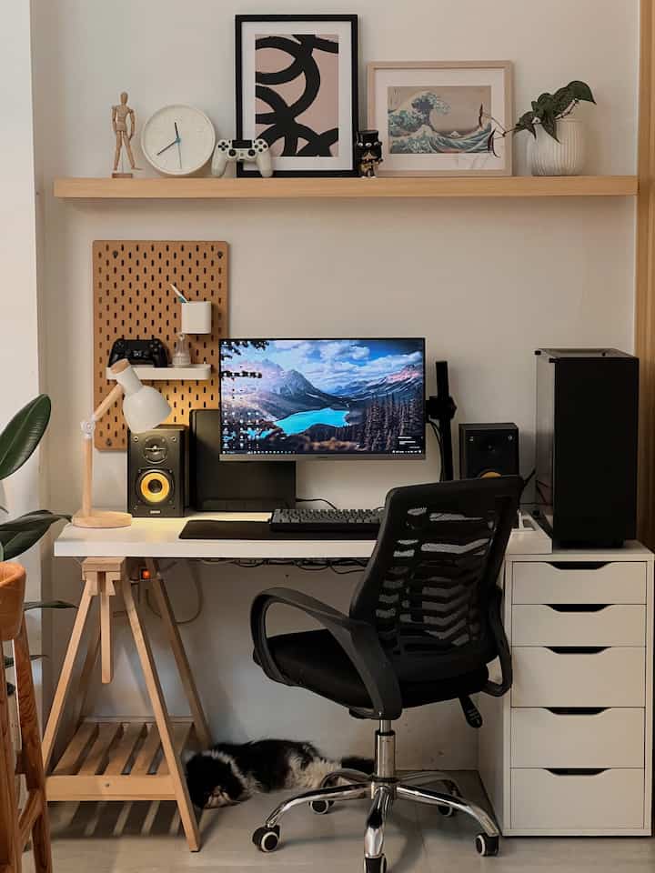 White and natural wood tone home office featuring desk, monitor, and office chair in a tidy workspace