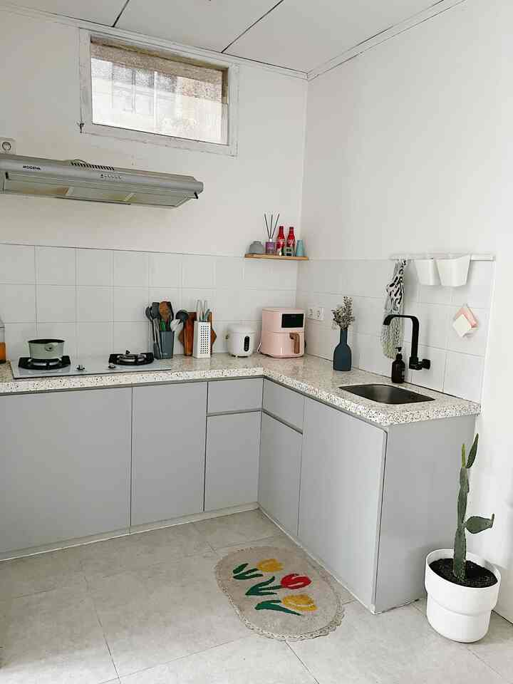 L-shaped kitchen in white and gray tones featuring modern minimal cabinetry and key cooking appliances with sleek, clean design