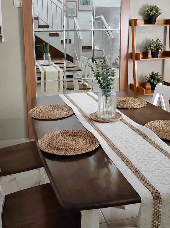 Wood-toned and white dining room for four, featuring a table runner and plant centerpiece in a clean, minimal setting