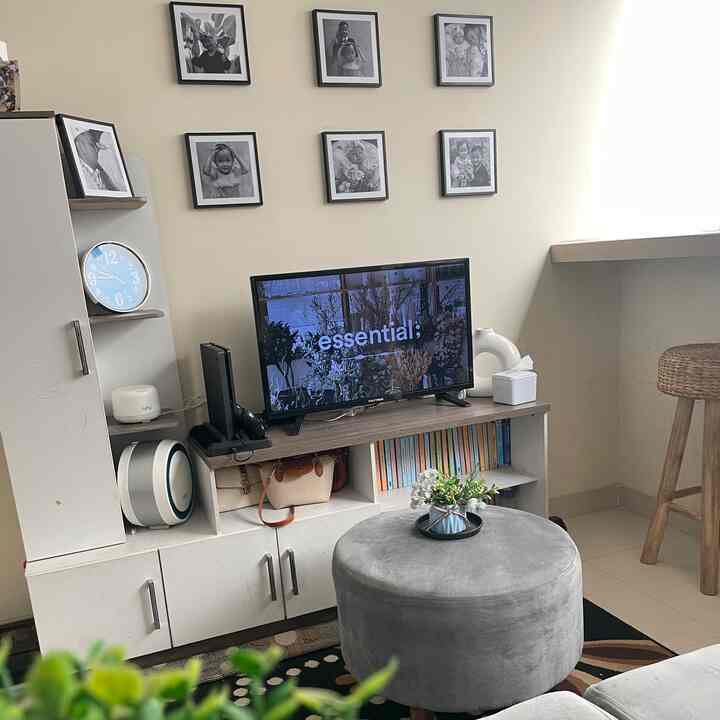 Living room with white walls and cabinetry, gray sofa and ottoman, creating a clean and cozy atmosphere