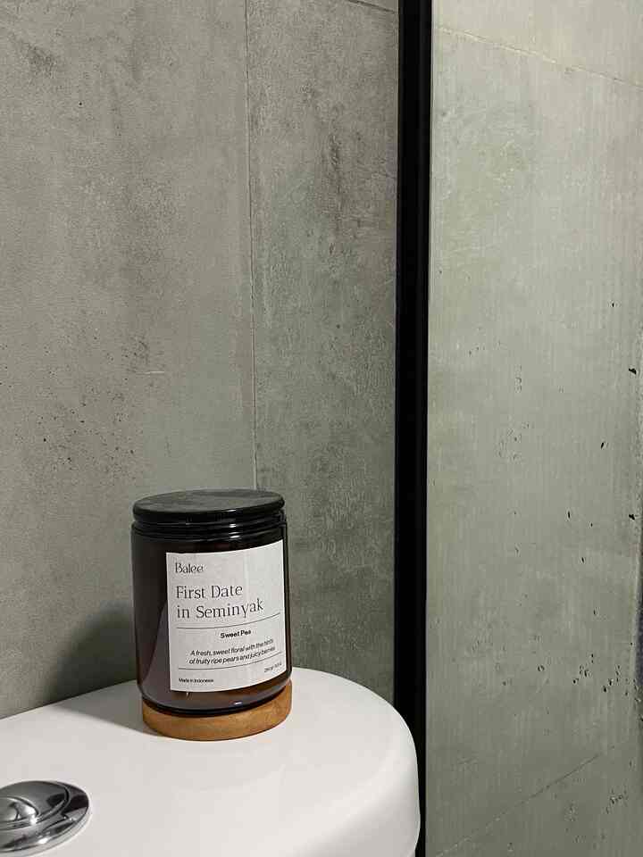 Gray-toned modern bathroom space featuring a brown candle jar on a white sink with a sleek and minimalistic atmosphere