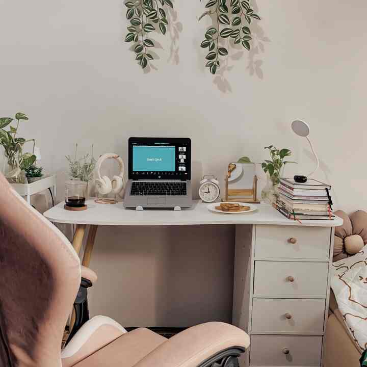 White and beige toned compact bedroom featuring a desk and office chair with a neat remote work setup