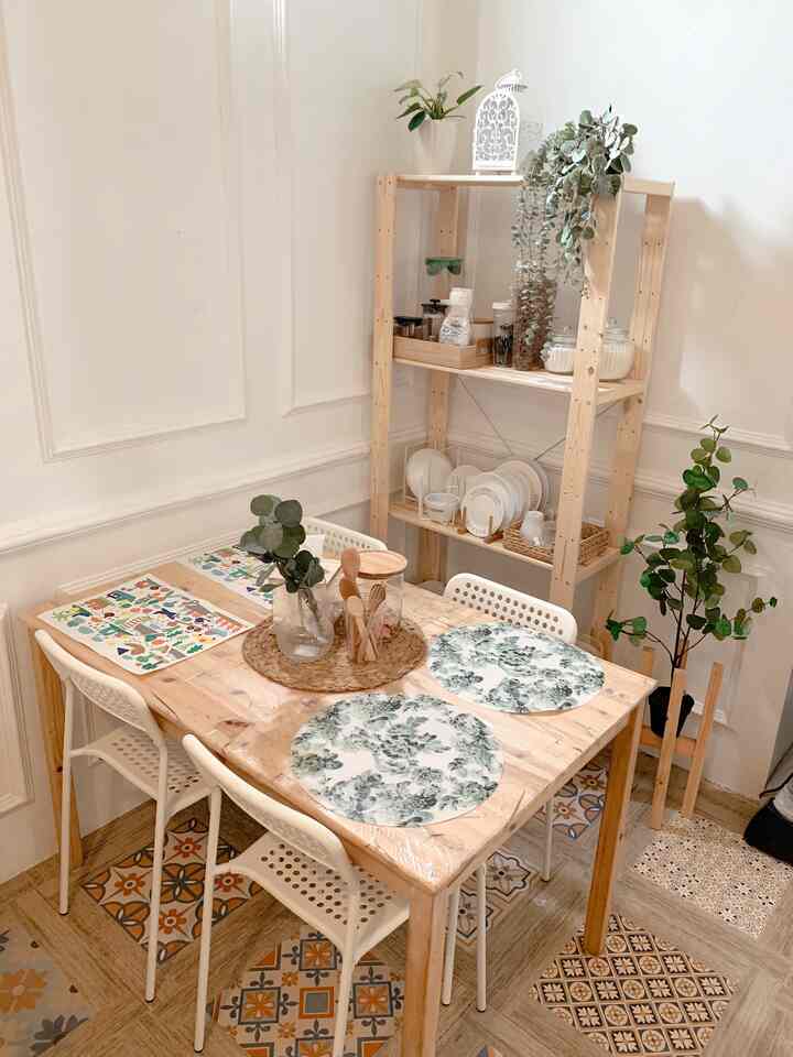 Bright wood tone and white dining room featuring a four-person table, shelving unit, and plants in a natural setting