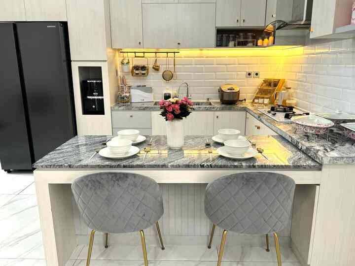 Modern kitchen in white and gray tones featuring a kitchen island set with dining chairs and tableware, clean and stylish layout