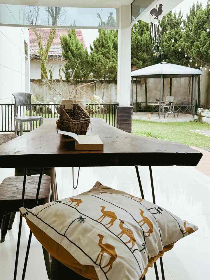 Yellow cushion on wood table in outdoor balcony space with garden and gazebo, creating a peaceful atmosphere