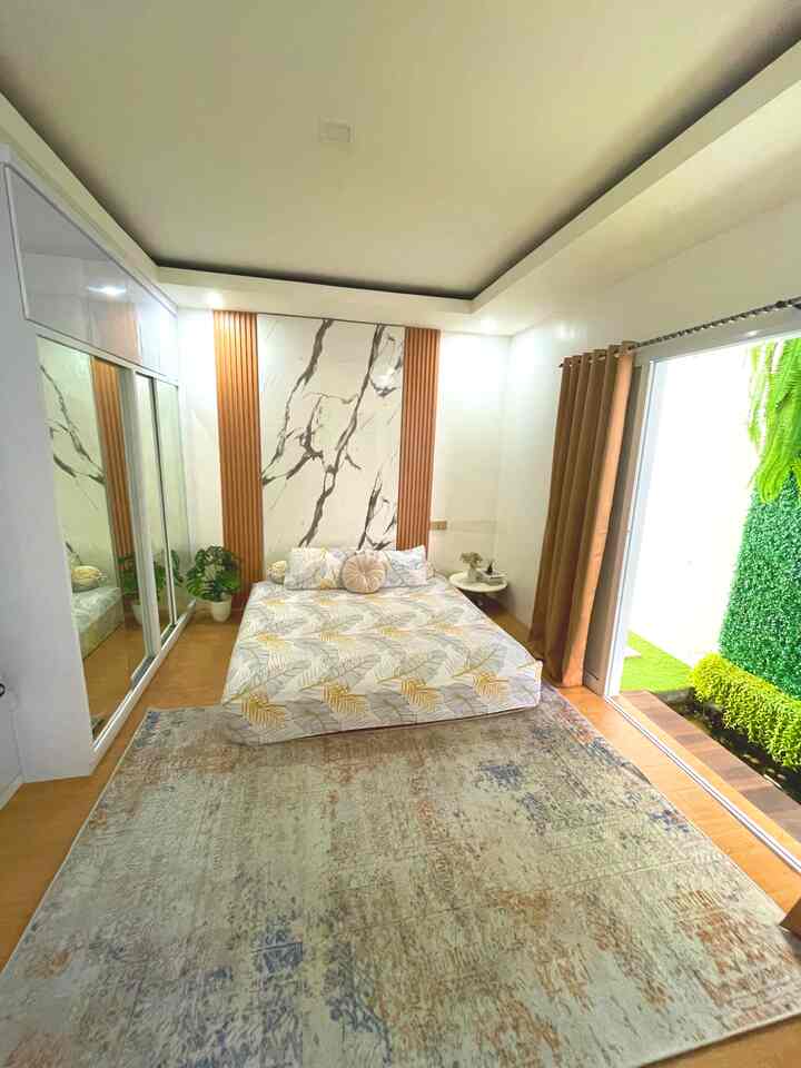 Bright and cozy bedroom with beige flooring, white walls, and a centrally placed bed