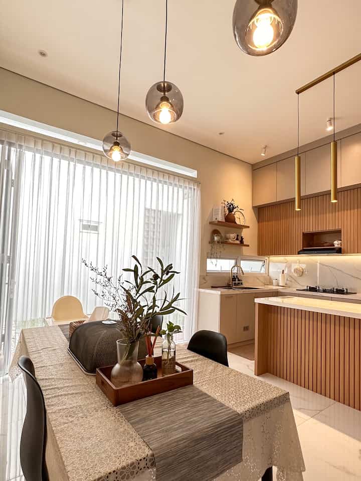 Bright dining room and kitchen featuring warm wood tones and white colors, pendant lights add cozy atmosphere in spacious clean space